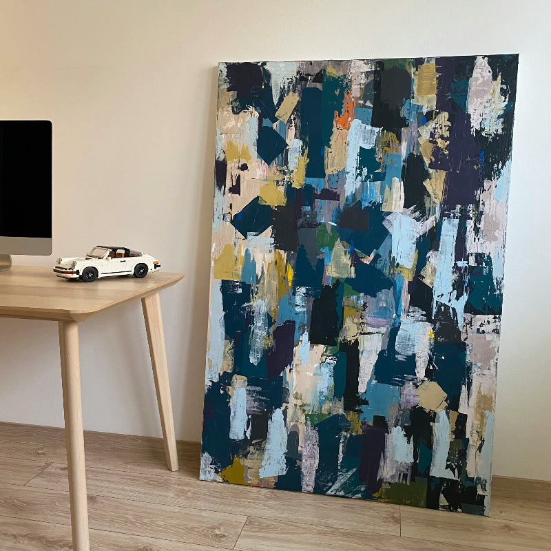 Abstract art piece on a wall next to a wooden table with a toy car.